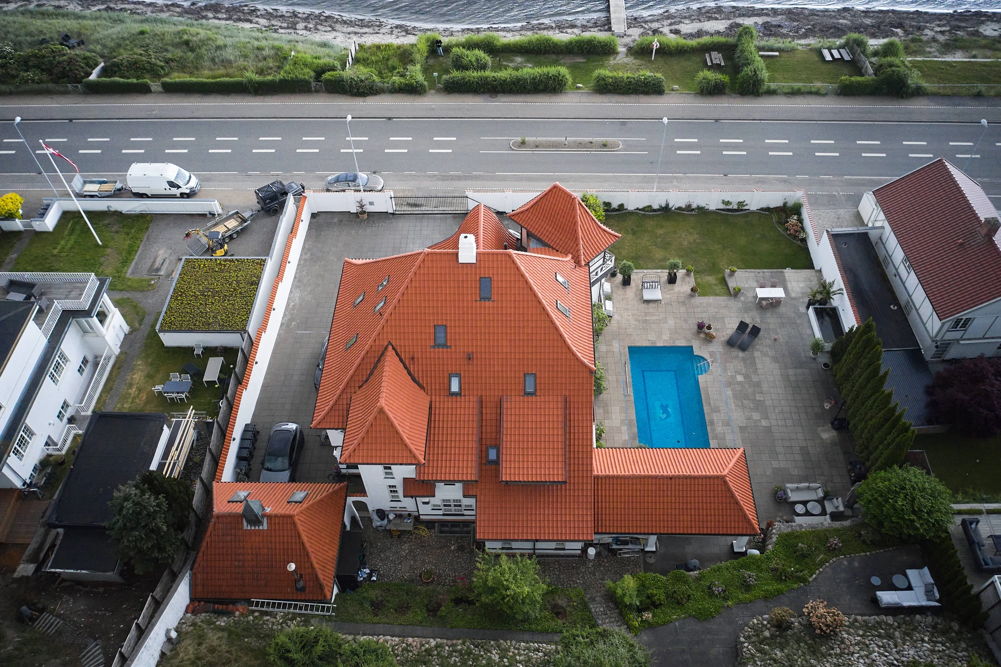Palæets røde tegltag, pool og terrasse med Øresund i baggrunden