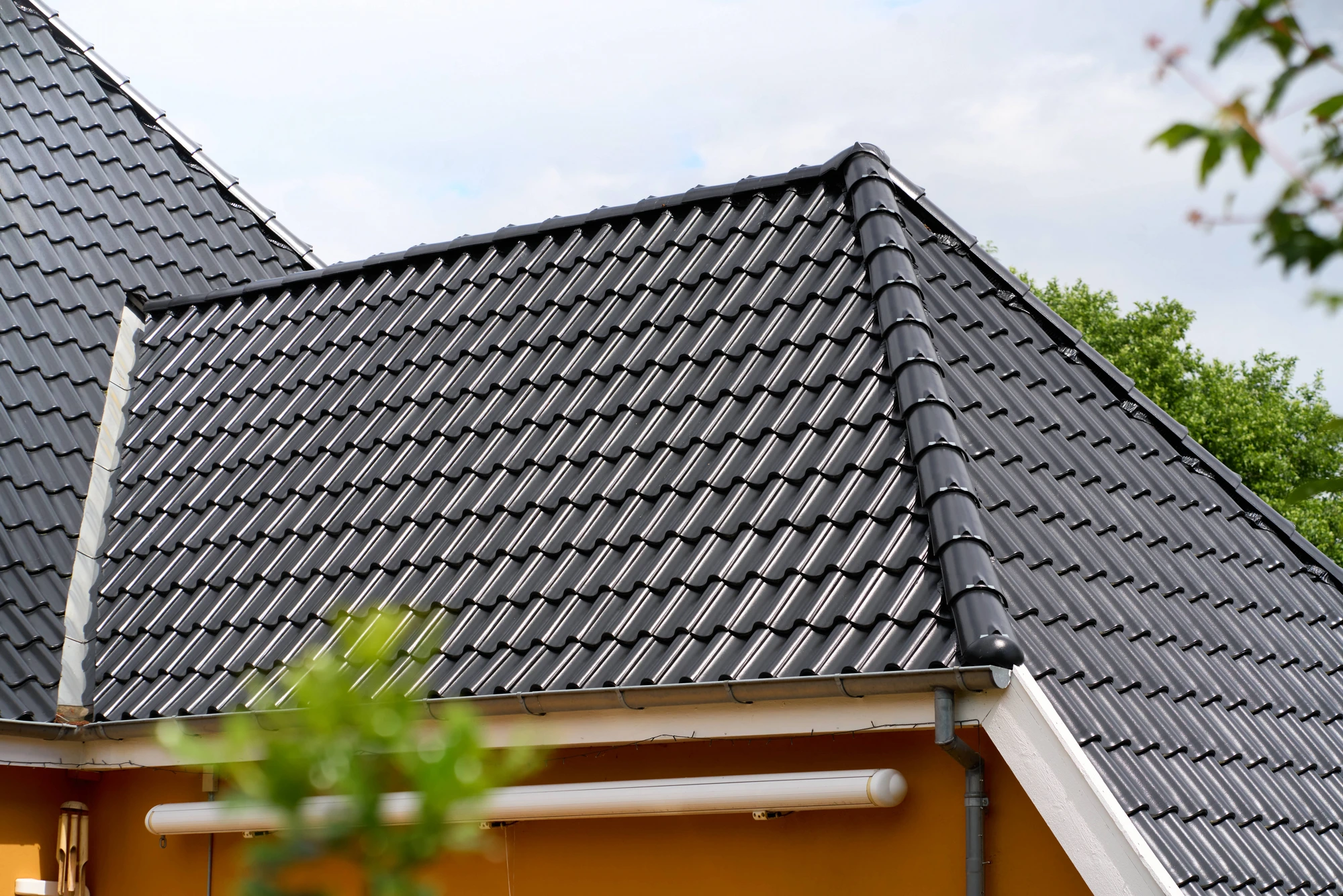 Detalje af det sorte, blanke tegltag med rygning og grat