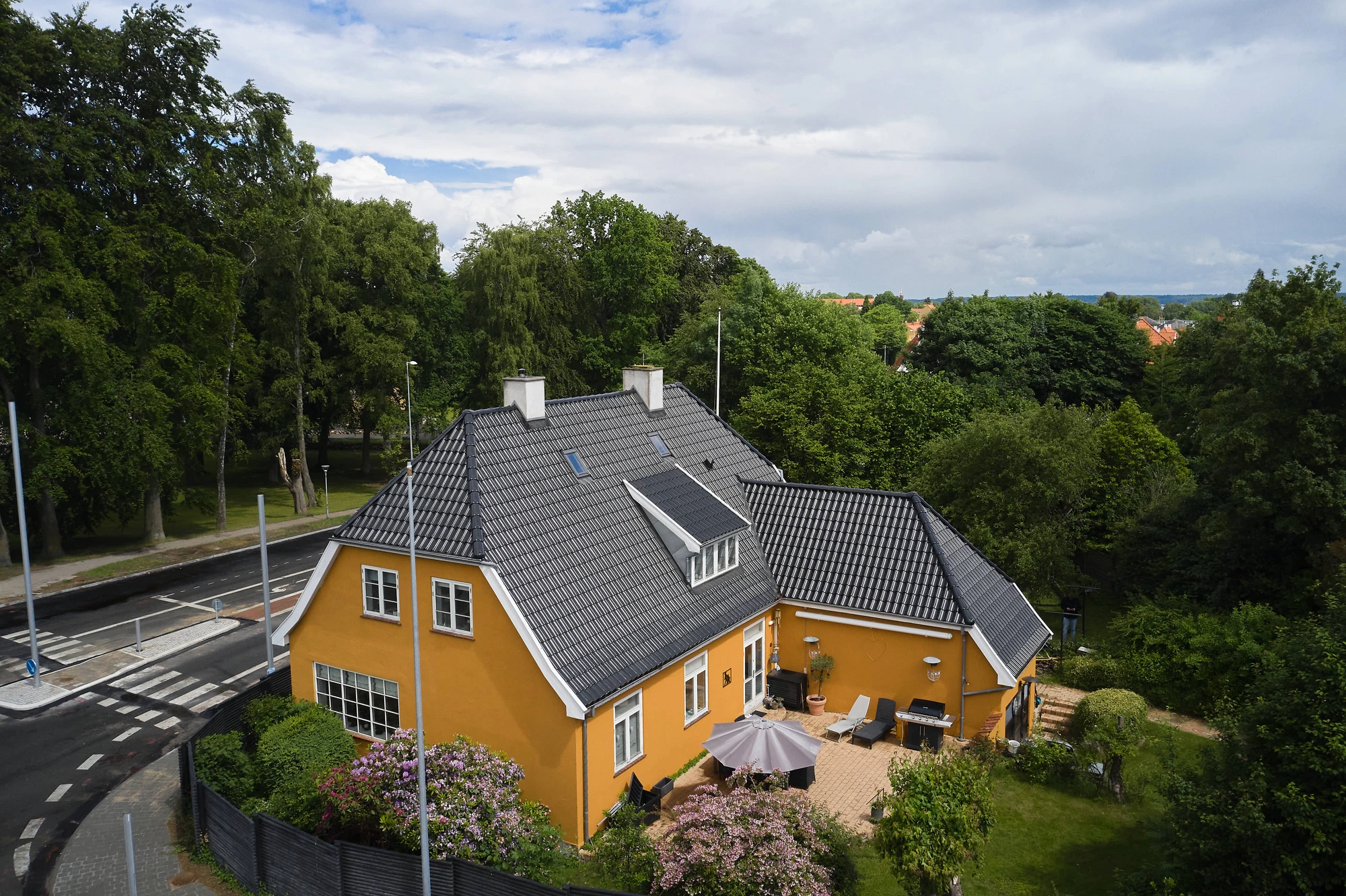 Villaen med det nye sorte tegltag set fra oven med den frodige have