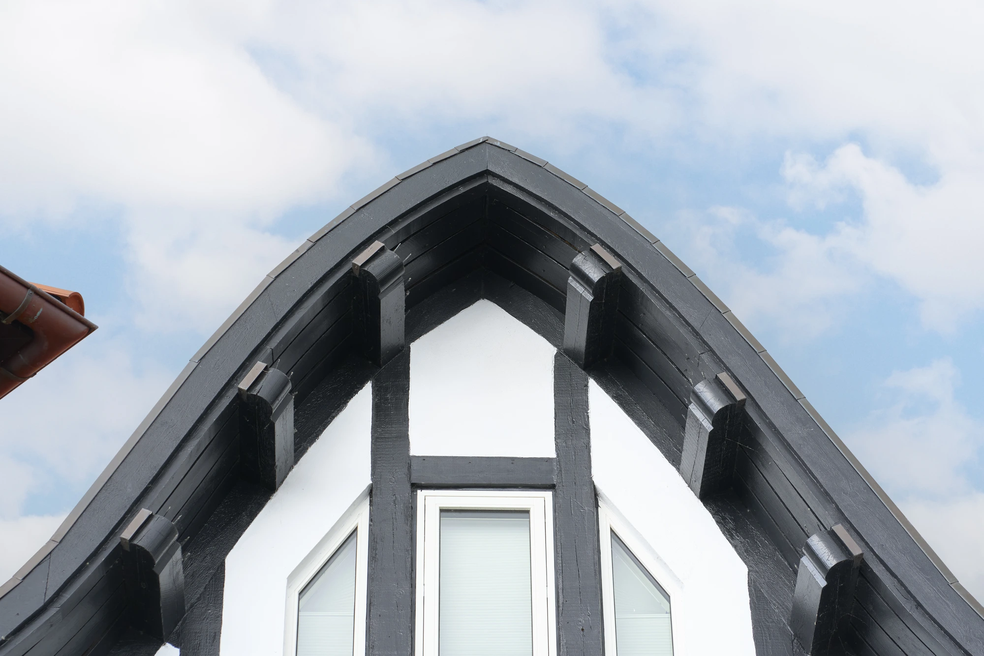 Detalje af sort bindingsværksgavl og rødt tegl mod himlen