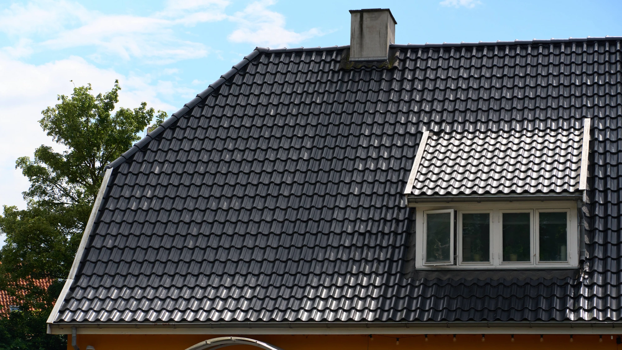 Gavl og kvist med sort tegltag set fra terrassen