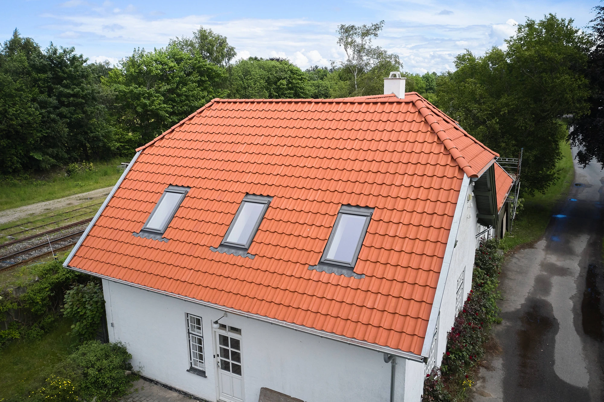 Luftfoto af stationsbygningens røde tegltag og de tilstødende jernbanespor
