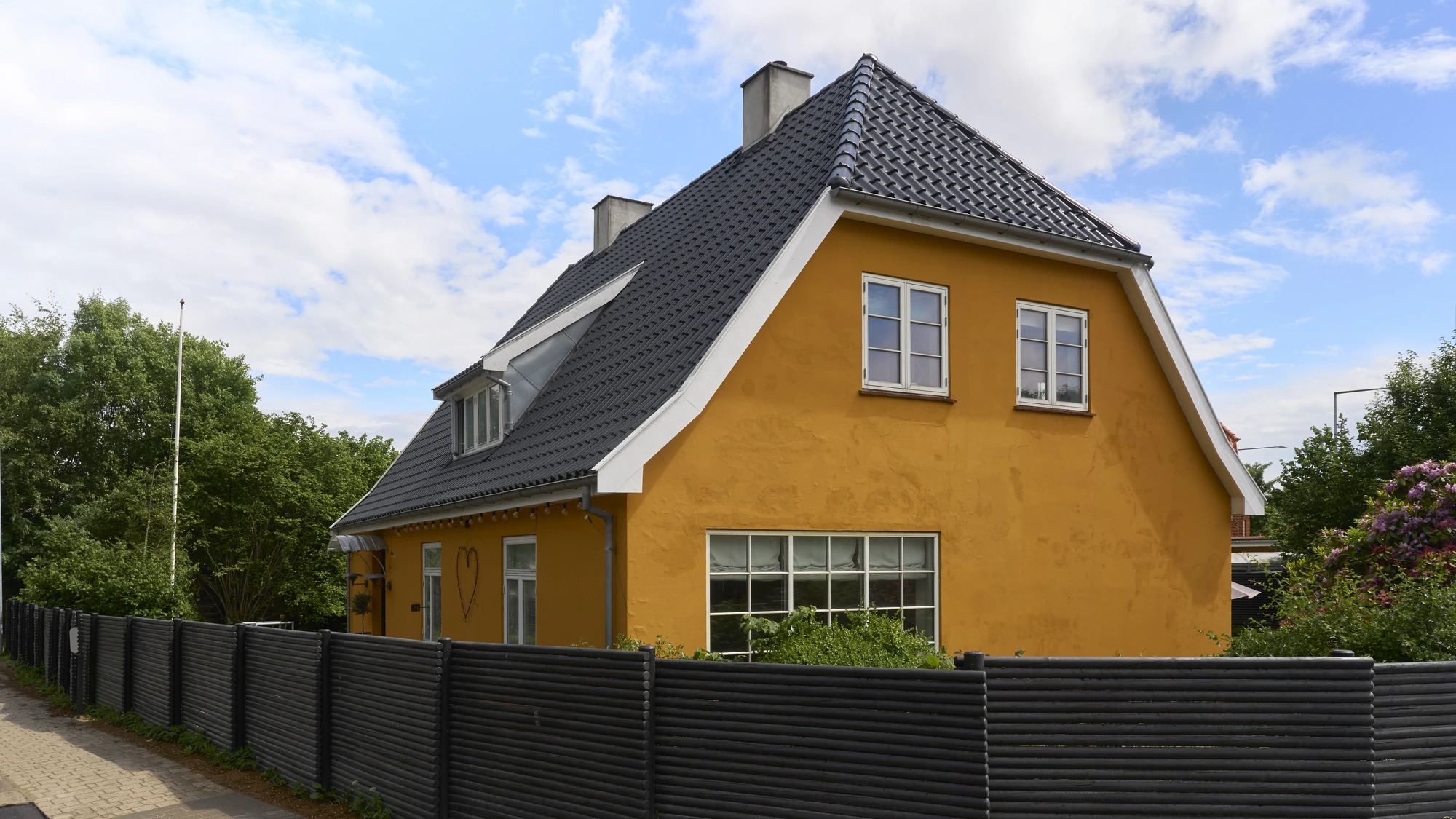 Den gule 30'er-villa med nyt sort tegltag set fra vejen