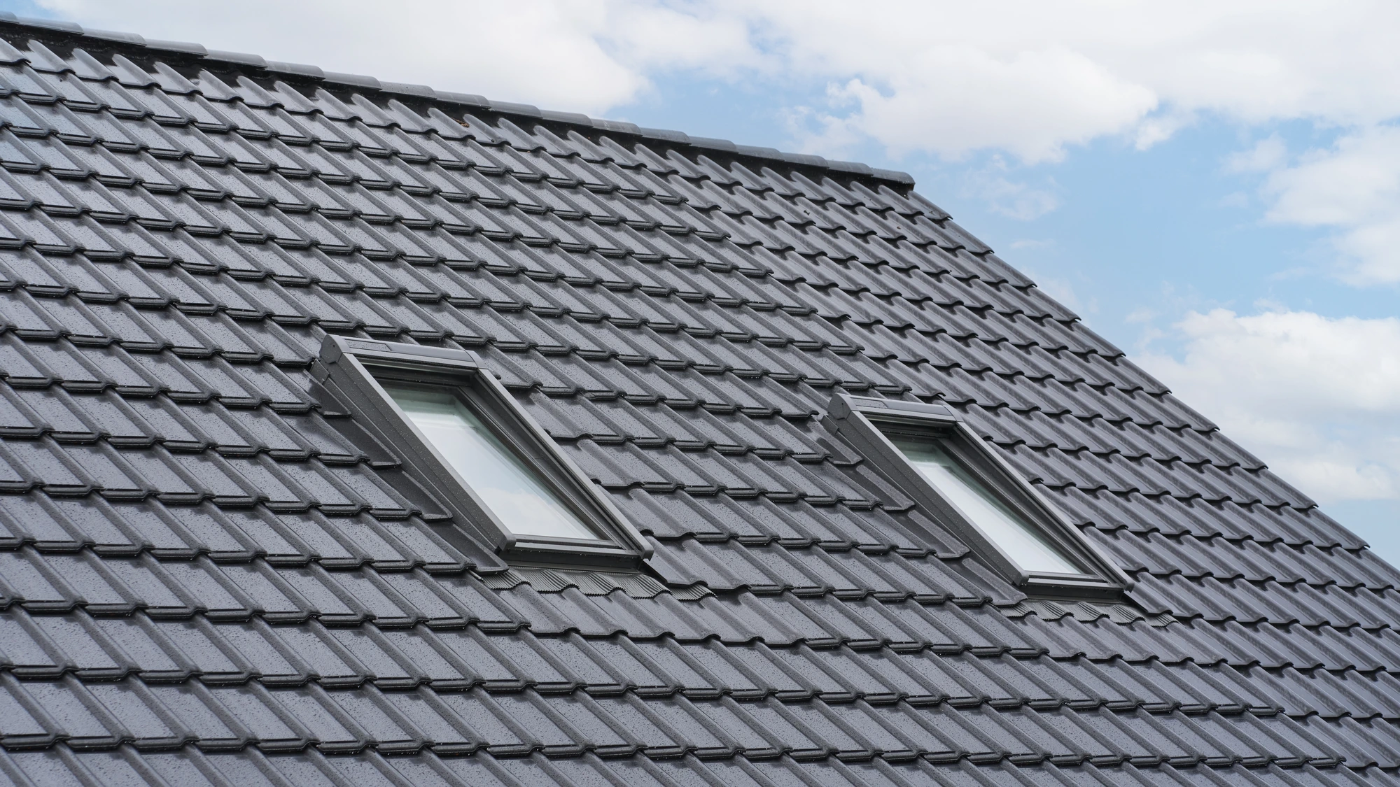 Det sorte tegltag med ovenlysvinduer set tæt på mod himlen