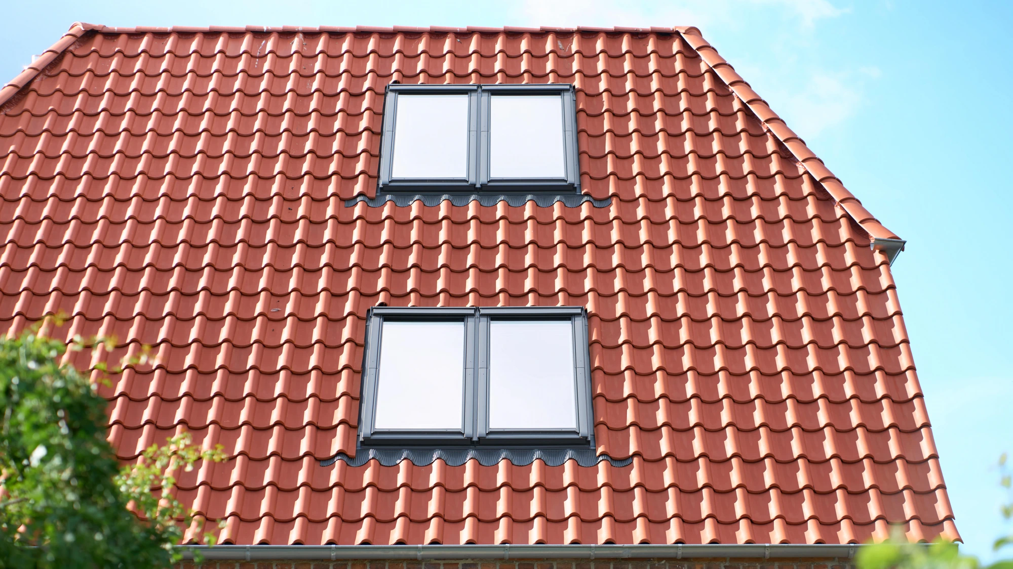 Villaens røde tegltag set gennem havens træer